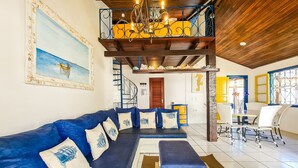 Un salon avec un canapé bleu, un plafond en bois et un escalier menant à un niveau supérieur.