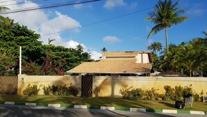 A residential property with a tiled roof, a gated entrance, and a well-maintained garden with various plants and flowers.