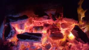 A close-up of burning wood with visible flames and glowing embers.