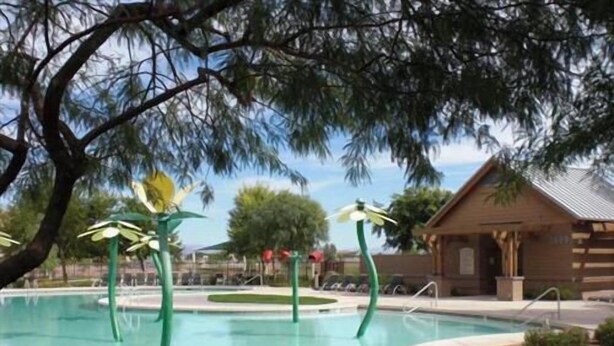 A swimming pool with green decorative elements, a wooden building, and a tree in the background. - Your Backyard Oasis Waiting ..., beautiful home in an award winning community (Gilbert)