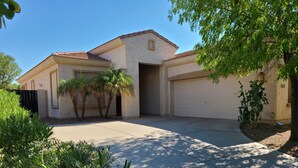 A two-story house with a garage, surrounded by palm trees and other greenery. - Your Backyard Oasis Waiting ..., beautiful home in an award winning community (Gilbert)