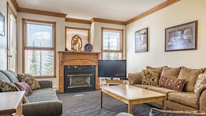 Una sala de estar acogedora con chimenea, asientos cómodos y ventanas amplias.