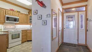 Una cocina con armarios de madera, microondas y horno. Hay cuadros en la pared y un adorno con forma de pez.