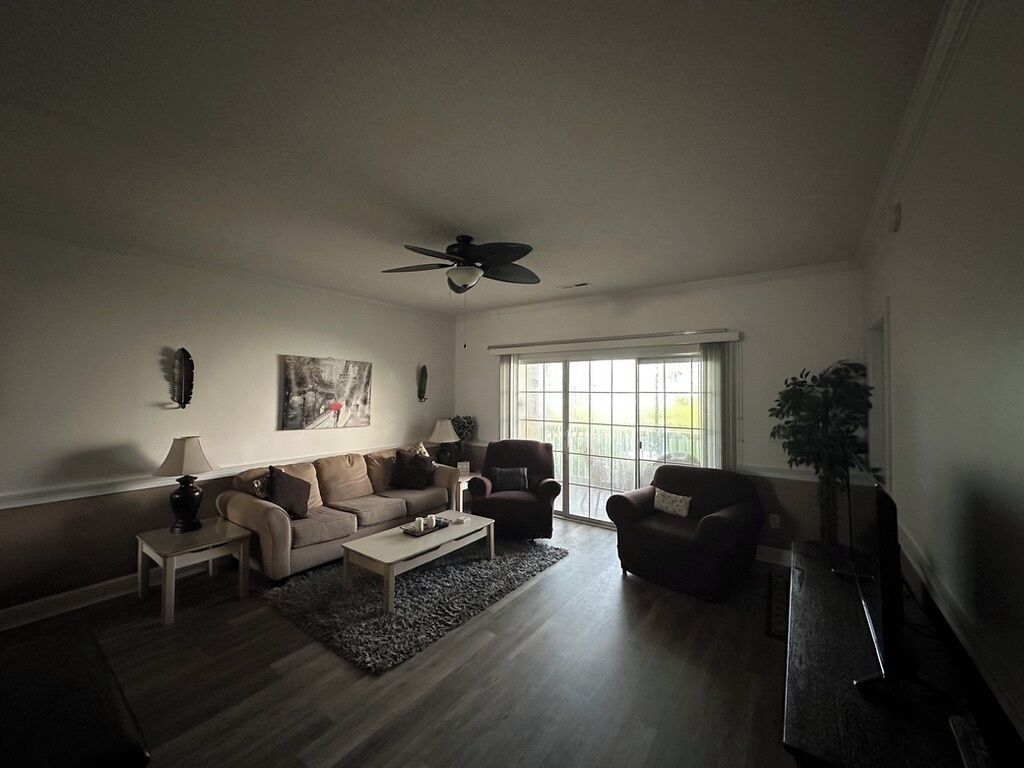 A living room with a ceiling fan, a sofa set, a coffee table, and a TV.
