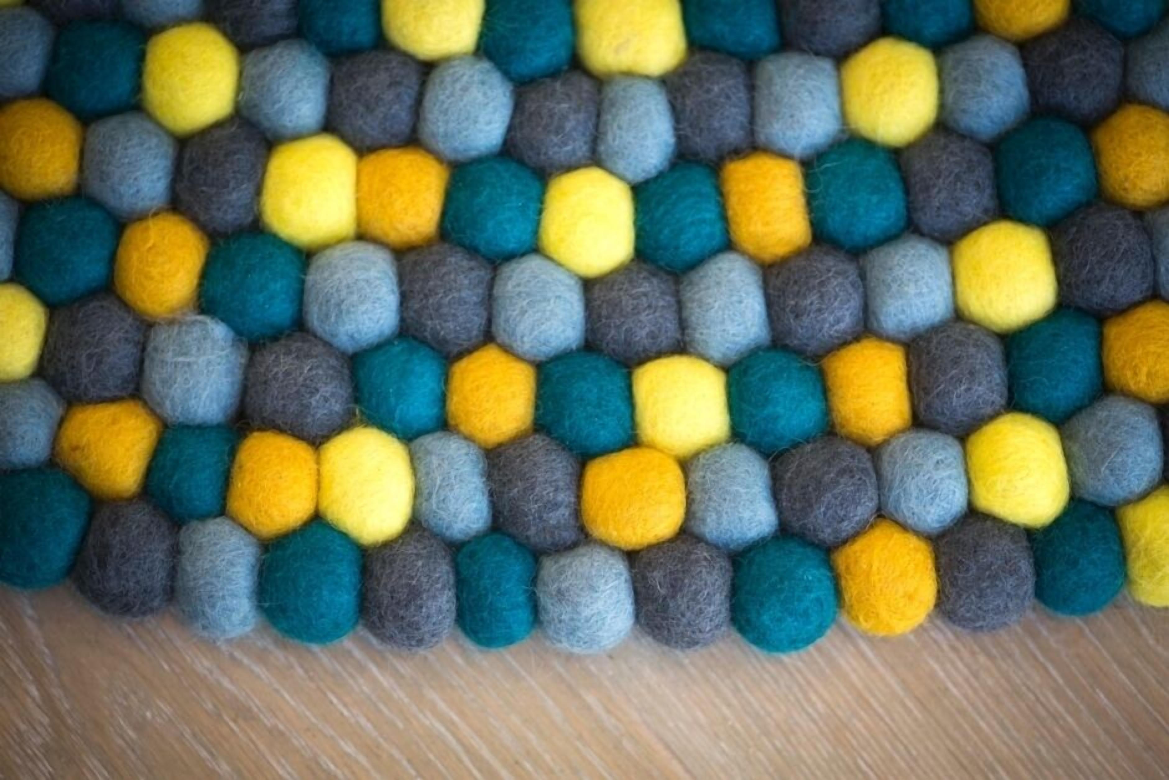 Un primo piano di un pannello feltro con motivo esagonale in tonalità di grigio, giallo e blu.