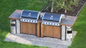 Un espace barbecue équipé de deux grils, d’une poubelle et d’un bac de recyclage.