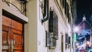 Una calle estrecha con una puerta de madera y un edificio blanco con una reja de metal.