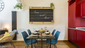 Un comedor con una pizarra que muestra el texto 'home sweet home', una mesa de madera, sillas azules y un armario rojo.