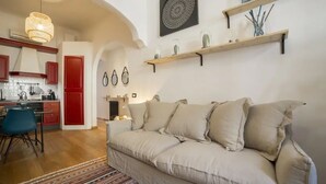 Un espacio de sala acogedor con un sofá, una mesa de comedor y una cocina al fondo.