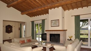 A living room with a fireplace, sofas, a coffee table, and a map on the wall. - Luxury Villa for 16 with Private Pool near Rome - Santa Cristina Estate (Magliano Sabina)