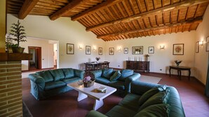 A spacious living room with a high wooden ceiling, green leather sofas, a white coffee table, and framed artwork on the walls. - Luxury Villa for 16 with Private Pool near Rome - Santa Cristina Estate (Magliano Sabina)