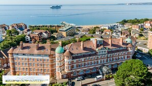 A large, historic building with multiple stories and a distinctive green dome, situated in a coastal town with a view of the sea and a cruise ship in the distance. - Luxury 2BR apartment 500m from beach and close proximity to New Forest  (Boscombe, Bournemouth)