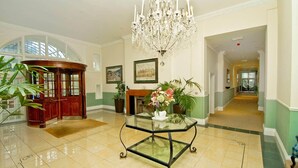 A spacious lobby with a glass coffee table, a grand chandelier, and a wooden reception desk. - Luxury 2BR apartment 500m from beach and close proximity to New Forest  (Boscombe, Bournemouth)
