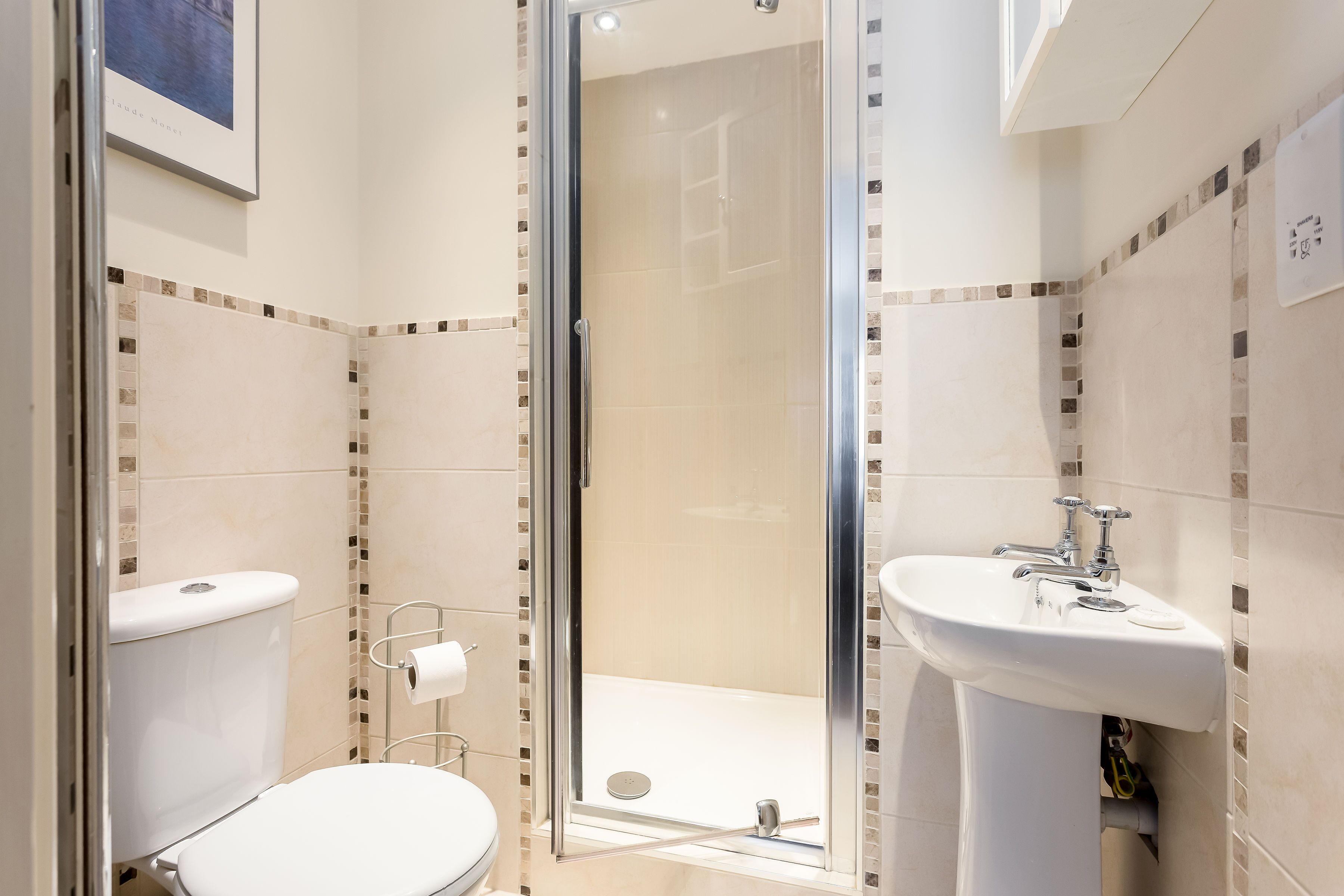 A modern bathroom with a glass-enclosed shower, a toilet, and a sink.