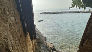 Una scala in pietra conduce a una vista sul mare, con cielo sereno e acqua calma.