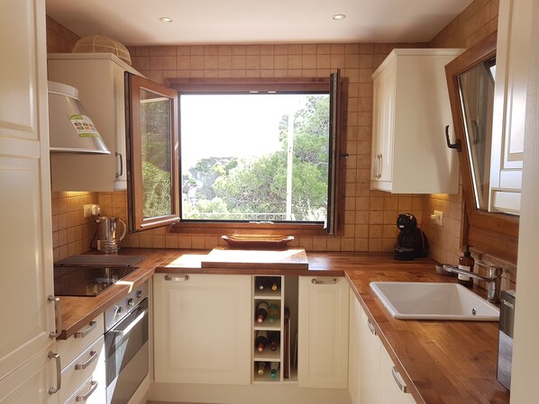A modern kitchen with wooden countertops, a built-in wine rack, and a window with a view of greenery. - Sea views, 2 Mins Walk to the Sea, Heated Pool, Air Con, Fibre WiFi, 90+ reviews (Aiguafreda, Begur)