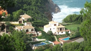 Una propiedad costera con varias edificaciones, una piscina y vistas al mar.