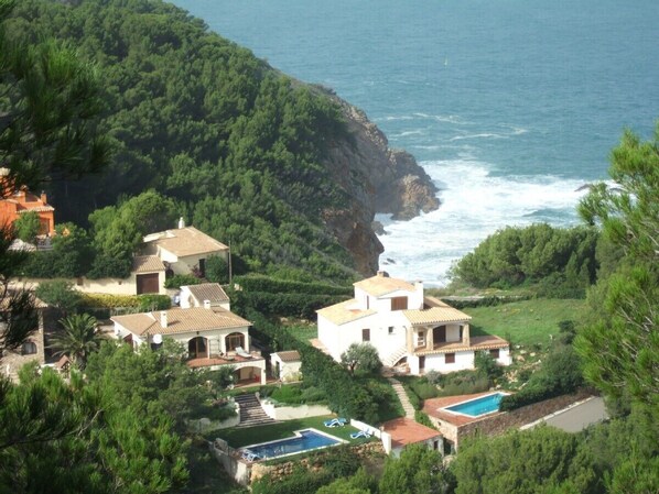 A coastal property with multiple buildings, a swimming pool, and a view of the sea.