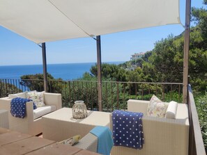A covered outdoor seating area with wicker furniture, a table, and a view of the sea. - Sea views, 2 Mins Walk to the Sea, Heated Pool, Air Con, Fibre WiFi, 90+ reviews (Aiguafreda, Begur)