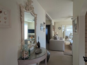 Un'ampia zona giorno con un grande specchio, un tavolo con piano in vetro e un divano.