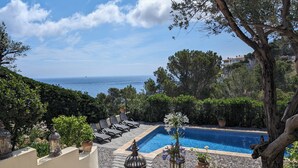 Zona de piscina con sillones de descanso, una piscina pequeña y vista al mar.