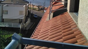 Zona residencial amb teulades de terracota, cel blau i vista al mar.