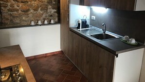 A modern kitchen with a stone wall, wooden cabinets, a stainless steel sink, and a coffee machine.