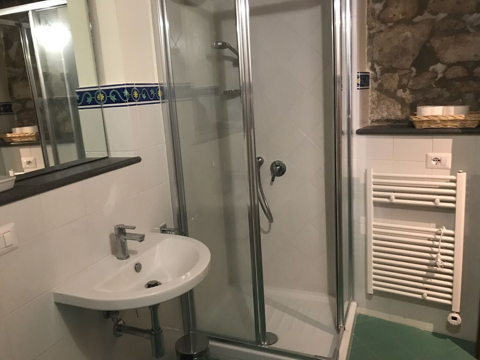 A bathroom with a glass-enclosed shower, a white sink, and a towel rack.
