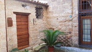 A stone building with a wooden door, a potted plant, and a metal gate.
