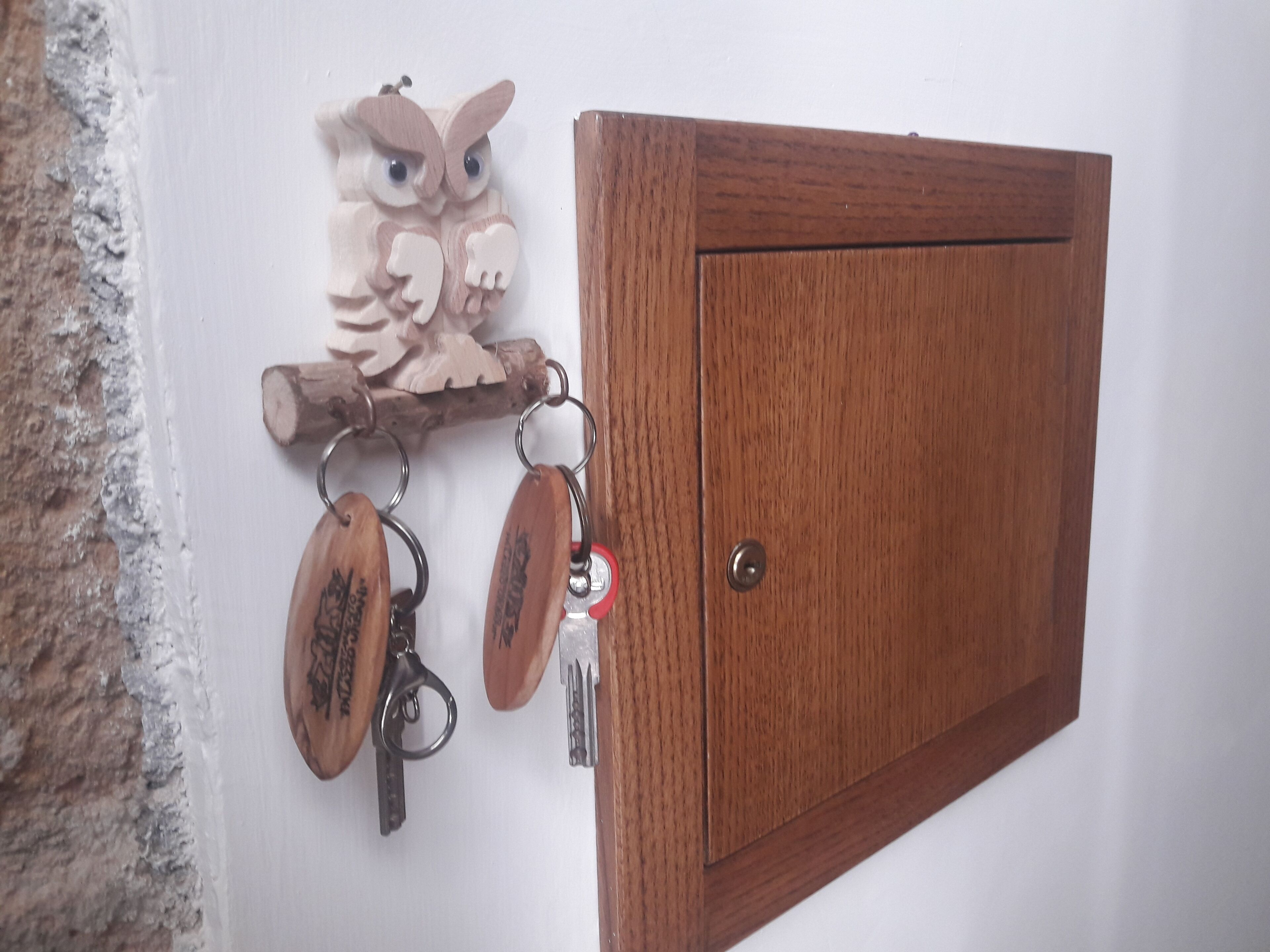 A wooden cabinet with a keyhole and a keychain with wooden keys and a key fob.