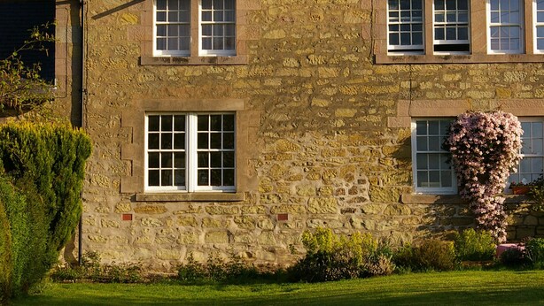 A stone building with a tiled roof, multiple windows, and a well-maintained lawn. - Tastefully renovated, ideally located cottage for a peaceful or active break. (Cornhill-on-Tweed)
