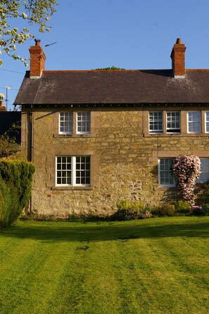 A stone building with a tiled roof, multiple windows, and a well-maintained lawn. - Tastefully renovated, ideally located cottage for a peaceful or active break. (Cornhill-on-Tweed)