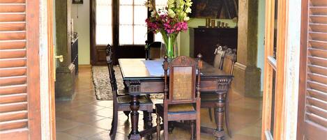 An open doorway leading to a dining area with a table and chairs, a vase of flowers, and a fireplace in the background.