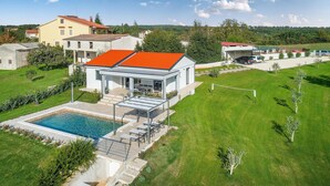 Une maison moderne dotée d’une piscine, d’un patio couvert et d’une pelouse bien entretenue.