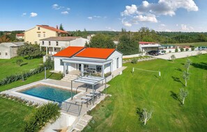 A modern house with a swimming pool, a covered patio, and a well-maintained lawn.
