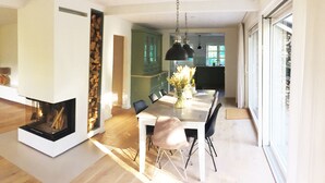 Un espace repas moderne avec une cheminée, une table entourée de chaises et une vue sur la cuisine.