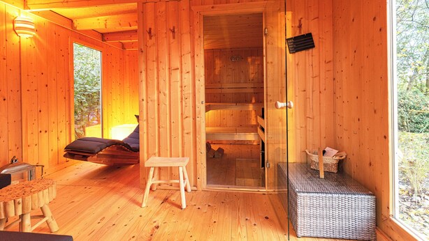 L’intérieur d’un chalet en bois comprend un sauna, une petite table et un banc.