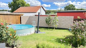 Un jardin avec une piscine, une terrasse en bois et un mur en briques.