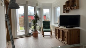 Une pièce comprenant une télévision, une chaise, une plante en pot et un meuble en bois.