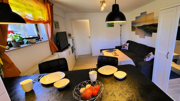 A compact living space with a dining area, a sofa, and a TV. - Great basement apartment in the middle of the island of Rügen in the outskirts of a village near mountains (Parchtitz)
