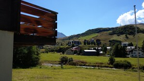 Un pueblo rural con casas en una ladera, una estructura de madera en primer plano y un cielo azul despejado.