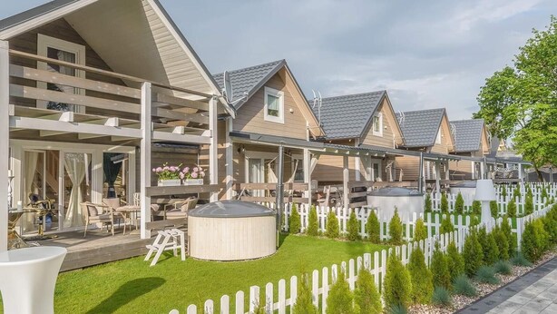 A residential area with multiple houses, a well-maintained lawn, and a white picket fence. - Woodhouse Resort Dobrogoszcz (Dobrogoszcz)