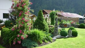 A well-maintained garden with a variety of plants and a stone wall. - Beautiful, exclusively furnished apartment with 4 edelweiss  (Umhausen)