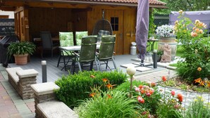 A wooden cabin with a patio, outdoor seating, and a garden with flowers and plants. - Beautiful, exclusively furnished apartment with 4 edelweiss  (Umhausen)