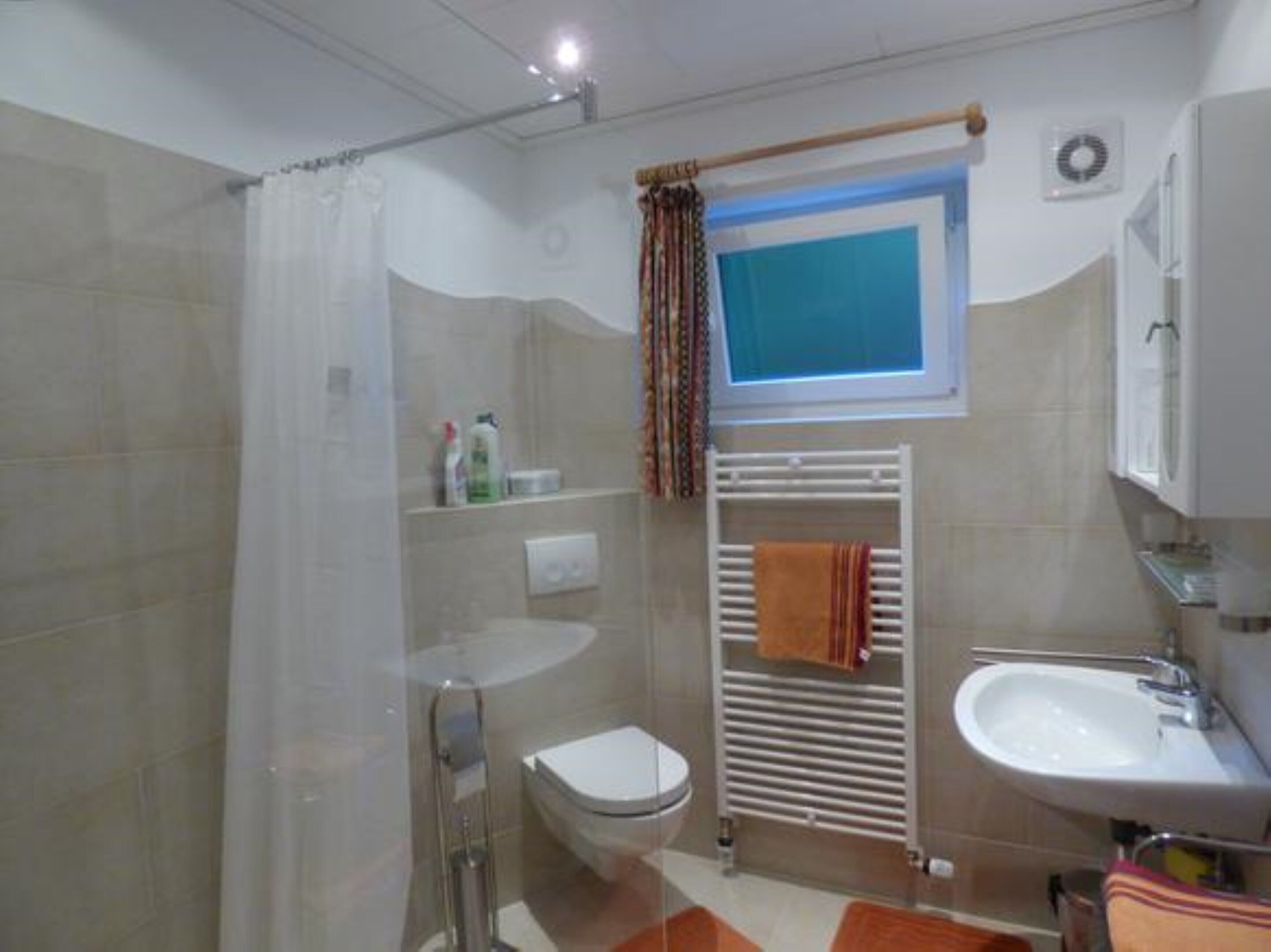 A bathroom with a shower, toilet, sink, and towel rack.