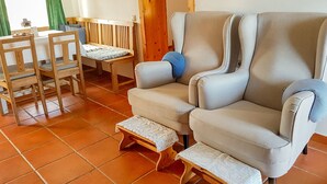 A cozy living room with a sofa, wooden chairs, a small table, and a bench.
