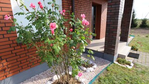 Un bâtiment en briques doté d’un jardin agrémenté de rosiers roses et d’un sentier en gravier.