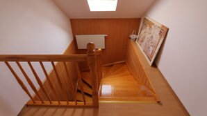 Un escalier en bois, une lucarne, un radiateur et un tableau encadré au mur.