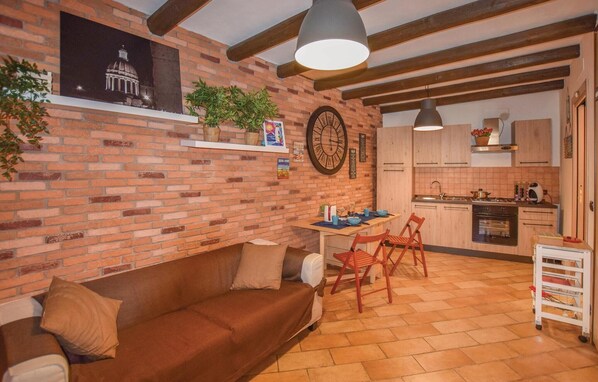 A cozy living room with a brick wall, a large clock, and a dining area with a table and chairs. - 2 bedroom lovely home in Ragusa RG (Ragusa RG)