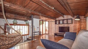 A spacious living area with a brick wall, wooden ceiling beams, a sofa, and a television. - 2 bedroom lovely home in Ragusa RG (Ragusa RG)